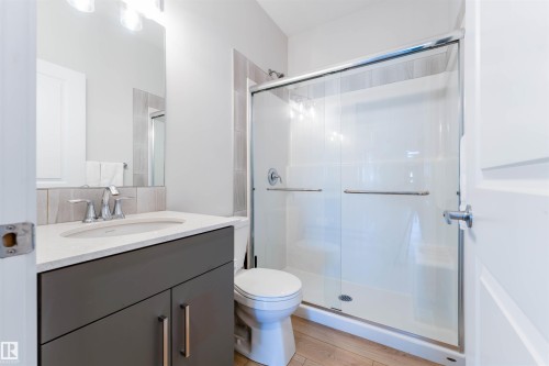 Bathroom featuring a vanity with a white countertop and undermount sink, a chrome faucet, and a large mirror - 8426 228A Street Nw, Edmonton, AB - Indoor Photo Showing Bathroom