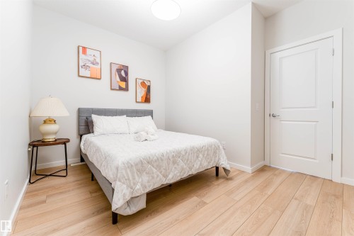 Bright room featuring light wood-finish flooring, white walls, and a white two-panel interior door with brushed nickel hardware - 8426 228A Street Nw, Edmonton, AB - Indoor Photo Showing Bedroom