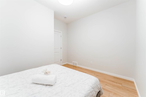 Bright interior space featuring light wood-finish flooring, white baseboards, and a white paneled door - 8426 228A Street Nw, Edmonton, AB - Indoor Photo Showing Bedroom