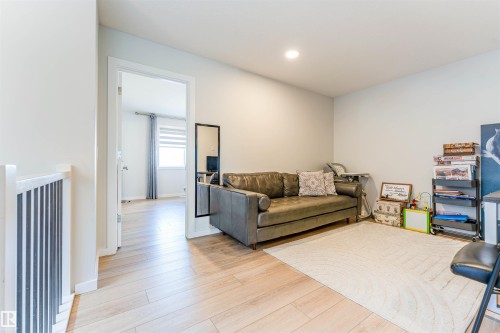 Versatile loft space featuring wood-finish flooring, recessed lighting, and a white baluster railing - 8426 228A Street Nw, Edmonton, AB - Indoor