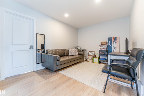 Versatile interior space featuring light wood-finish flooring, recessed lighting, and a white paneled door - 8426 228A Street Nw, Edmonton, AB - Indoor