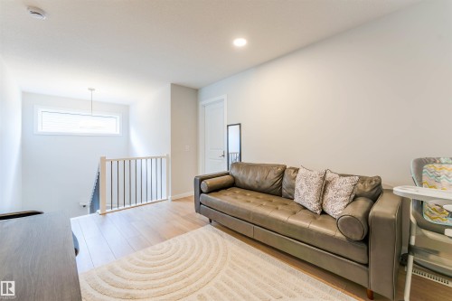 Upper-level landing featuring wood-finish flooring, a contemporary staircase with wood newel posts and black metal spindles, a transom window, and recessed lighting - 8426 228A Street Nw, Edmonton, AB - Indoor Photo Showing Living Room