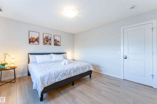 Spacious room featuring light wood-finish flooring, light-colored walls, a ceiling-mounted light fixture, a paneled interior door, and baseboard trim - 8426 228A Street Nw, Edmonton, AB - Indoor Photo Showing Bedroom