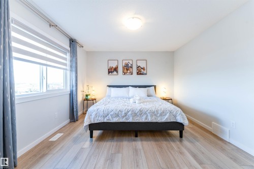 Spacious room featuring light wood-finish flooring, a large window with horizontal blinds and drapery, and a flush-mount ceiling light fixture - 8426 228A Street Nw, Edmonton, AB - Indoor Photo Showing Bedroom