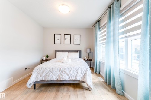 Bright interior featuring wood-finish flooring, white walls, and a contemporary ceiling light fixture - 8426 228A Street Nw, Edmonton, AB - Indoor Photo Showing Bedroom