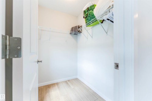 Walk-in closet featuring light wood-finish flooring, white walls, and built-in wire shelving - 8426 228A Street Nw, Edmonton, AB - Indoor