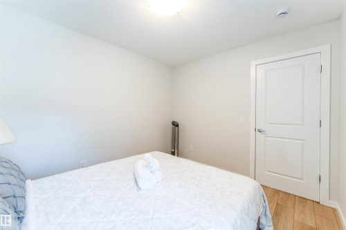 Bedroom featuring light wood-finish flooring, a white paneled door, and a flush mount ceiling light - 8426 228A Street Nw, Edmonton, AB - Indoor Photo Showing Bedroom