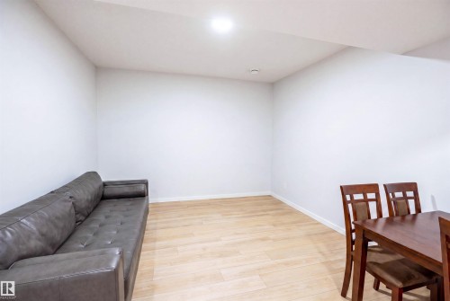 Spacious room with light wood-finish flooring and white baseboards, featuring recessed lighting - 8426 228A Street Nw, Edmonton, AB - Indoor