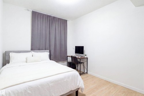 Room featuring wood-finish flooring, white walls, and a window with grey privacy curtains - 8426 228A Street Nw, Edmonton, AB - Indoor Photo Showing Bedroom