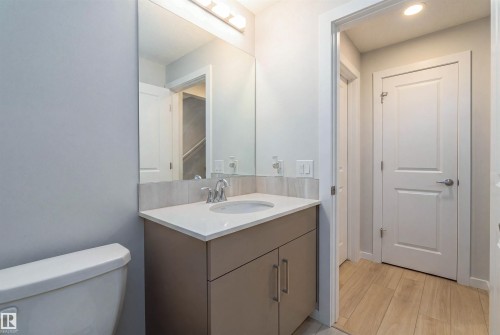 Bathroom with a single vanity, white countertop, and light wood-finish flooring - 8426 228A Street Nw, Edmonton, AB - Indoor Photo Showing Bathroom