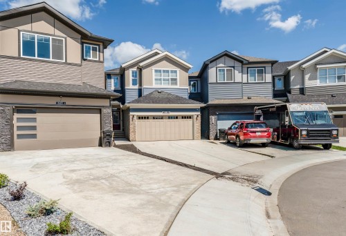 Contemporary two-story residence featuring a two-car garage with frosted window panels, stone veneer accents, and a concrete driveway - 8426 228A Street Nw, Edmonton, AB - Outdoor With Facade