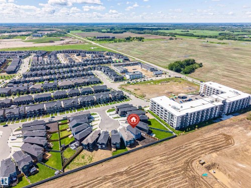Aerial perspective showcasing a residential development with single-family homes and a multi-story apartment building - 8426 228A Street Nw, Edmonton, AB - Outdoor With View