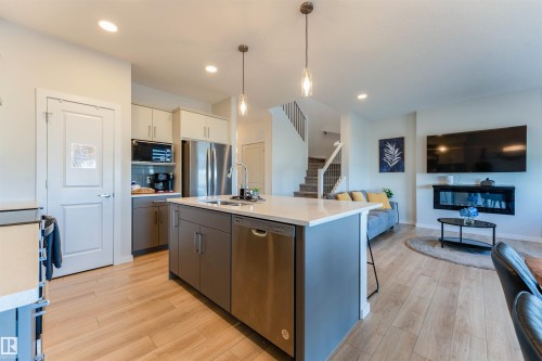 Open-concept kitchen and living area featuring wood-finish flooring - 8426 228A Street Nw, Edmonton, AB - Indoor Photo Showing Kitchen With Double Sink