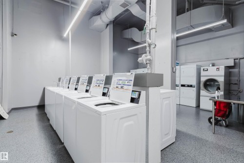 Dedicated laundry facility with multiple top-loading washing machines and front-loading dryers - 904 10883 Saskatchewan Drive, Edmonton, AB 