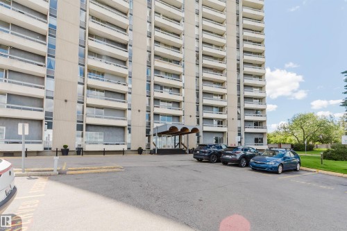 Multi-story building featuring numerous private balconies, a covered entrance, and a paved parking area - 904 10883 Saskatchewan Drive, Edmonton, AB 
