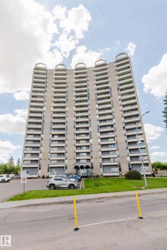 Multi-story residential building featuring a concrete facade with multiple balconies and a distinctive curved architectural element at the roofline - 904 10883 Saskatchewan Drive, Edmonton, AB 
