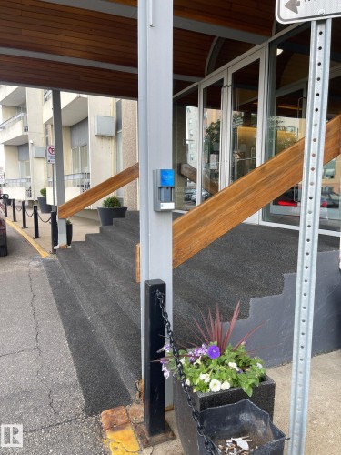 Building entrance featuring a covered walkway, wood-finish ceiling, glass doors, and a planter with seasonal greenery - 904 10883 Saskatchewan Drive, Edmonton, AB 