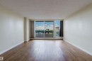 Spacious room featuring wood-finish flooring, white baseboards, and light-colored walls - 904 10883 Saskatchewan Drive, Edmonton, AB 