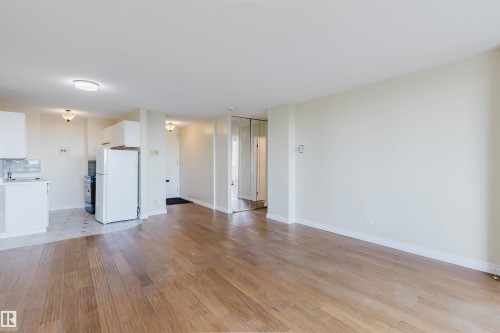 Spacious main living area featuring wood-finish flooring, light-toned wall paint, and white baseboards - 904 10883 Saskatchewan Drive, Edmonton, AB 