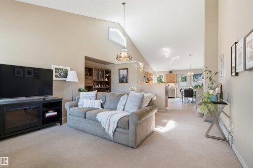 Vaulted ceiling living area featuring neutral carpeting and light-colored walls - 11715 11B Avenue, Edmonton, AB 