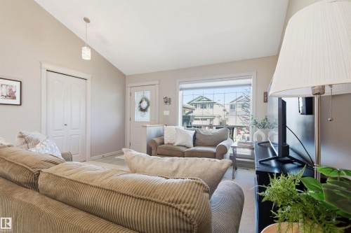 Vaulted ceiling with pendant lighting, light-toned walls, and a large window with white trim - 11715 11B Avenue, Edmonton, AB 