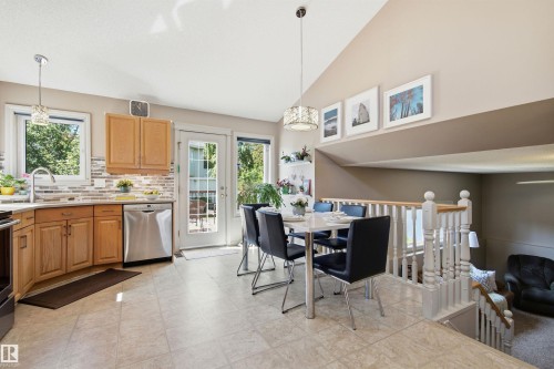 Kitchen and dining area featuring light wood cabinetry, stainless steel appliances, a tile backsplash, and a glass-paneled door - 11715 11B Avenue, Edmonton, AB 