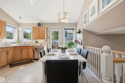 Open-concept kitchen and dining area featuring light wood cabinetry, stainless steel appliances, and a tiled backsplash - 11715 11B Avenue, Edmonton, AB 