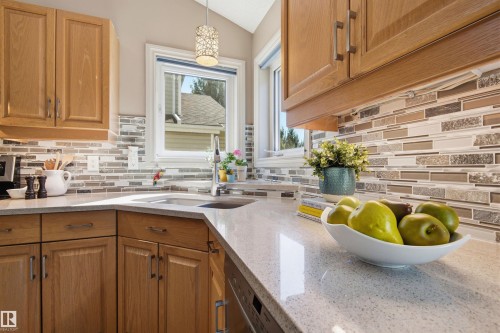 Kitchen featuring light wood cabinetry, a mosaic tile backsplash, and light-toned countertops - 11715 11B Avenue, Edmonton, AB 