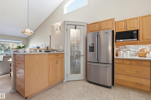 Kitchen featuring wood cabinetry, stainless steel appliances, and a tiled backsplash - 11715 11B Avenue, Edmonton, AB 