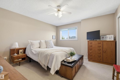 Bright bedroom featuring a white ceiling fan, light neutral wall paint, and a window with white trim - 11715 11B Avenue, Edmonton, AB 