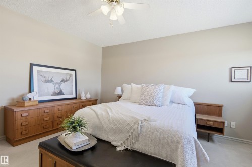 Neutral-toned room featuring a ceiling fan with integrated lighting, textured ceiling, and light-colored wall-to-wall carpeting - 11715 11B Avenue, Edmonton, AB 