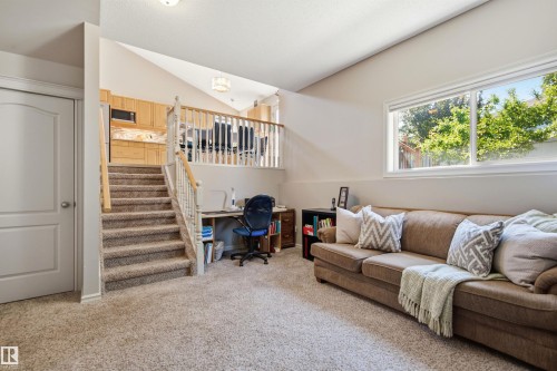 Carpeted staircase with white railings ascending to an upper level featuring a built-in kitchenette with light wood cabinetry - 11715 11B Avenue, Edmonton, AB 