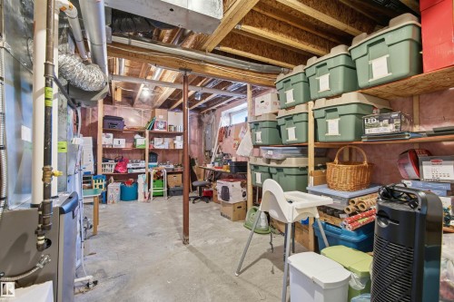 Unfinished basement featuring exposed wood framing, concrete flooring, and substantial built-in shelving - 11715 11B Avenue, Edmonton, AB 