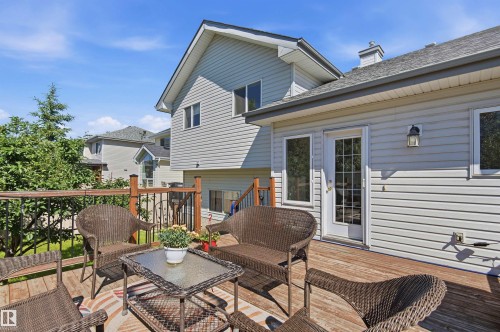 Expansive wood-finish deck featuring a wrought iron and wood railing, providing direct access to the interior through a multi-pane glass door - 11715 11B Avenue, Edmonton, AB 