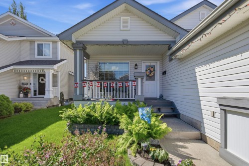 Light-colored siding exterior featuring a covered front porch with white railings and substantial columns - 11715 11B Avenue, Edmonton, AB 
