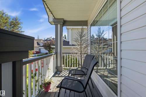 Porch featuring wood-finish decking, white vertical railing, and a large window with grid panes - 11715 11B Avenue, Edmonton, AB 