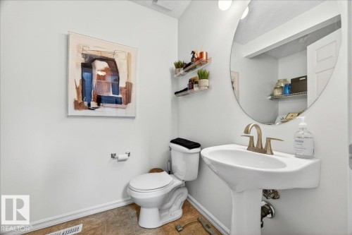Pedestal sink with brushed metal faucet and a large circular mirror - 3934 160 Avenue, Edmonton, AB 