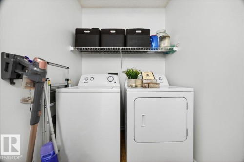 Dedicated laundry area featuring a white washing machine, white dryer, and an overhead wire storage shelf - 3934 160 Avenue, Edmonton, AB 
