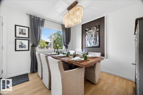 Dining area featuring wood-finish flooring, a rectangular window with dark drapery, and a chandelier with glass elements - 3934 160 Avenue, Edmonton, AB 