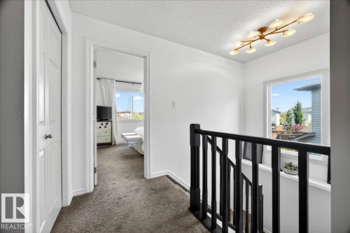 Upper-level landing featuring a contemporary semi-flush mount lighting fixture, black wood balustrade, and a window with a white frame - 3934 160 Avenue, Edmonton, AB 
