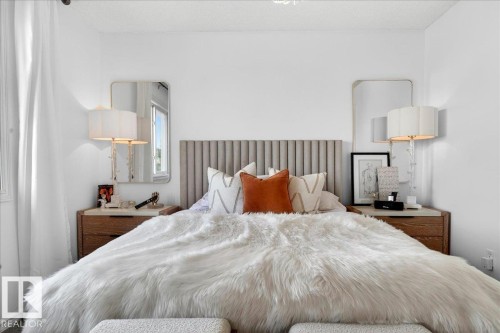 Bedroom featuring a channeled upholstered headboard, white walls, and a window with sheer curtains - 3934 160 Avenue, Edmonton, AB 