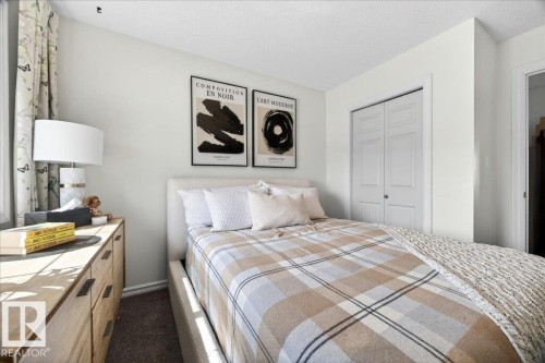 Bedroom featuring light neutral wall paint and carpeting, a window with patterned drapes, a built-in closet with bi-fold doors, and a wood-finish dresser with dark hardware - 3934 160 Avenue, Edmonton, AB 