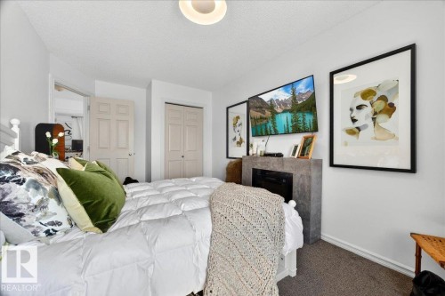 Bedroom featuring a built-in electric fireplace with a dark-toned surround, wall-mounted television, and neutral carpet flooring - 3934 160 Avenue, Edmonton, AB 