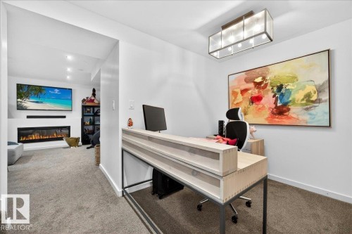 Carpeted room featuring a modern linear light fixture and a built-in electric fireplace - 3934 160 Avenue, Edmonton, AB 