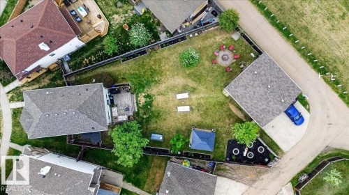 Expansive green backyard featuring a fire pit area, mature trees, and a wooden deck - 3934 160 Avenue, Edmonton, AB 