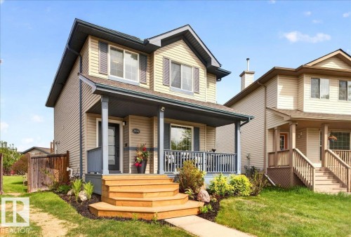 Two-story residence featuring light-toned siding, a covered front porch, and multi-pane windows with shutters - 3934 160 Avenue, Edmonton, AB 