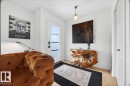 Entryway featuring wood-finish flooring, a contemporary pendant light fixture, a white paneled door, and a white entry door with frosted glass panels - 3934 160 Avenue, Edmonton, AB 