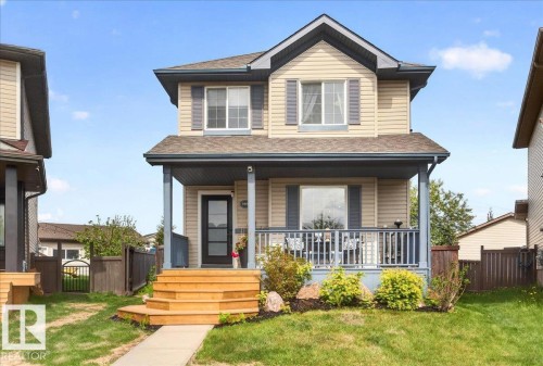 Two-story property featuring light-colored siding with contrasting dark shutters and a covered front porch - 3934 160 Avenue, Edmonton, AB 