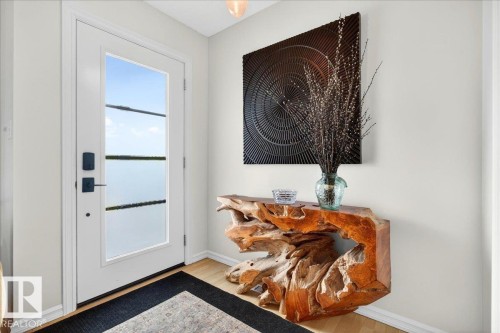 Entryway featuring a contemporary glass-paneled door with dark hardware, light wood-finish flooring, and light-toned wall finishes - 3934 160 Avenue, Edmonton, AB 