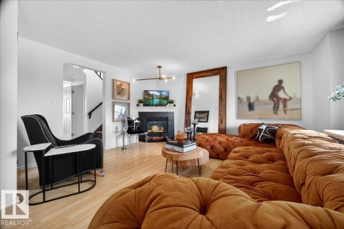 Living area featuring light wood-finish flooring and a fireplace with a dark tile surround - 3934 160 Avenue, Edmonton, AB 